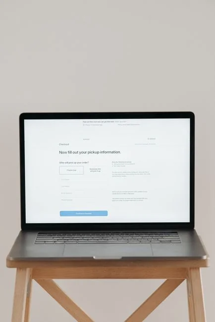 Individual on yoga mat practicing stretches alongside a laptop for online fitness classes.